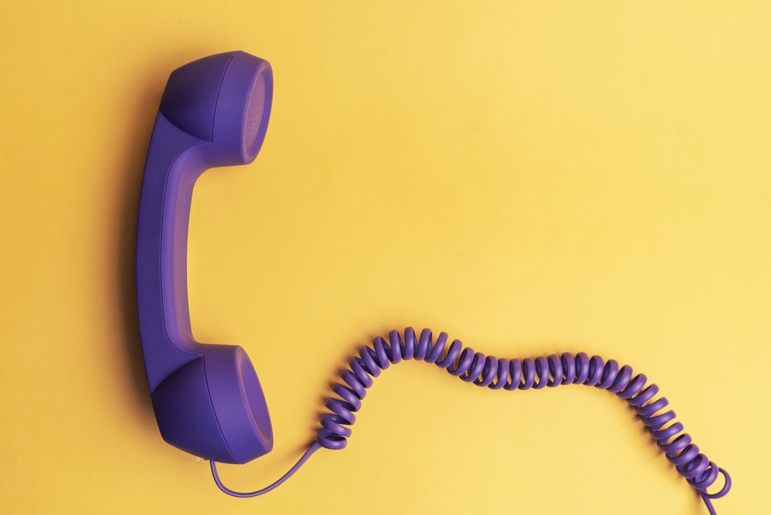 Purple telephone receiver on yellow background